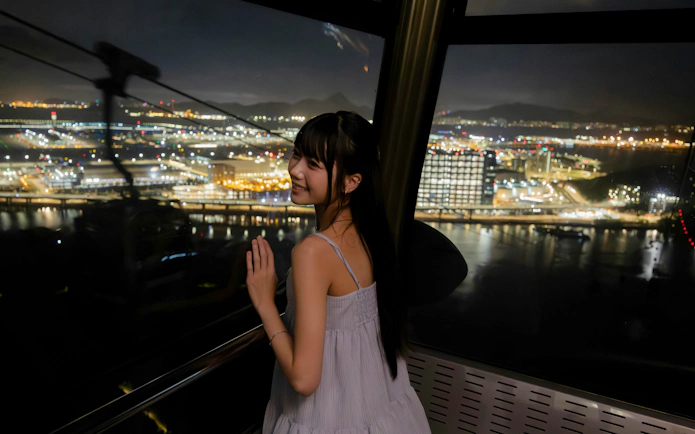 Tourist enjoying night view from Ngong Ping 360 cable car on Lantau Island.