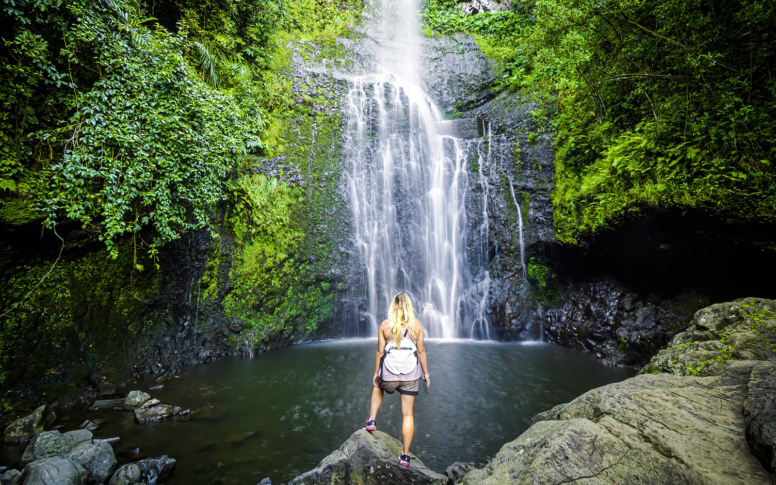 Person standing by a waterfall on Hana Highway, Maui, Hawaii.