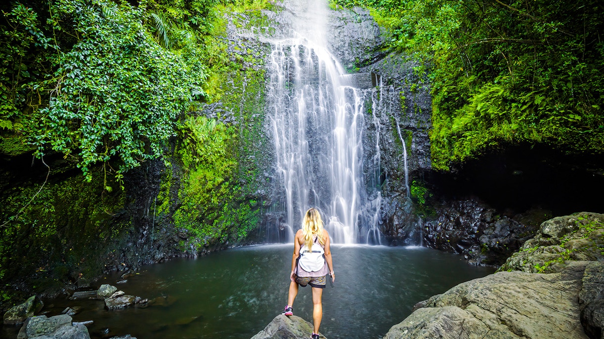 Person standing by a waterfall on Hana Highway, Maui, Hawaii.