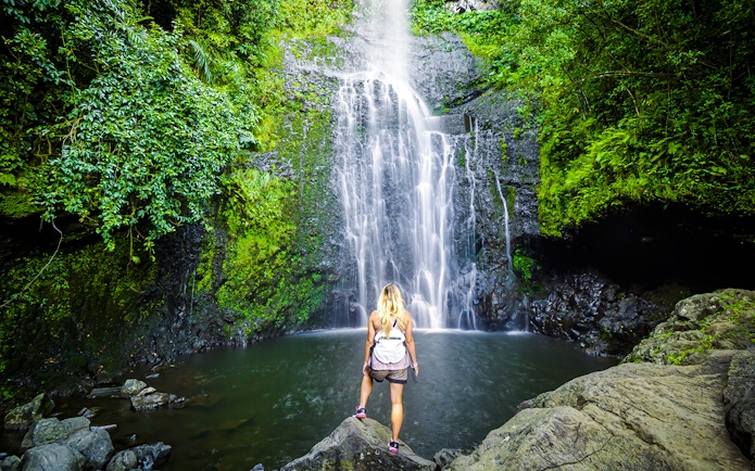 Person standing by a waterfall on Hana Highway, Maui, Hawaii.
