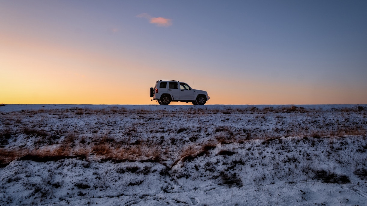 Car driving on a snowy road at dawn in winter, Iceland.