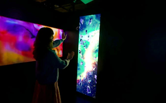 Guest interacting with digital art display at ARTECHOUSE DC exhibit.