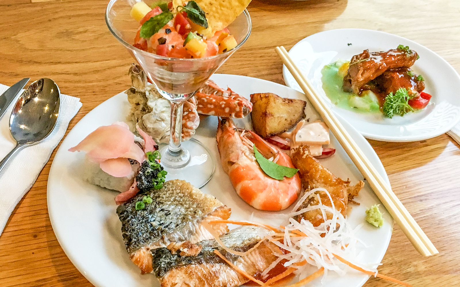 Catamaran sailing near Santorini coastline with passengers enjoying lunch on deck.