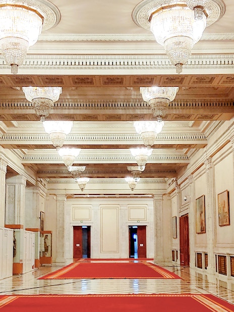 Hallway with chandeliers and red carpet in the Palace of Parliament, Bucharest.
