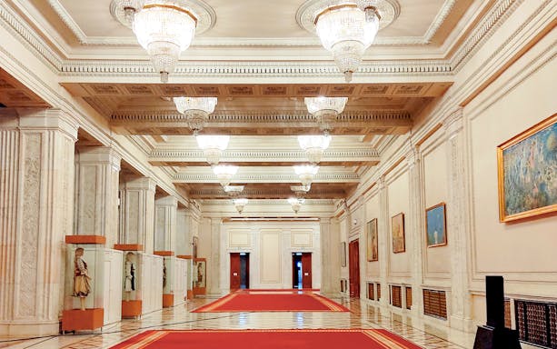 Hallway with chandeliers and red carpet in the Palace of Parliament, Bucharest.