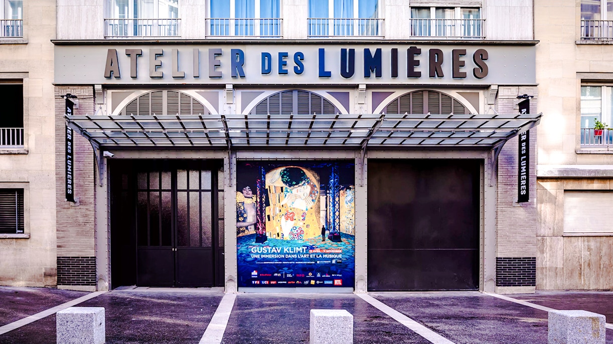 Exterior of Atelier Des Lumières in Paris with Gustav Klimt exhibition poster.