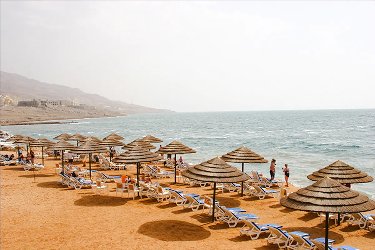 Sun loungers and parasols on a sandy beach by the Dead Sea, Amman.