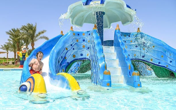 Child sliding down a colorful water slide at Makadi Water World, Hurghada.