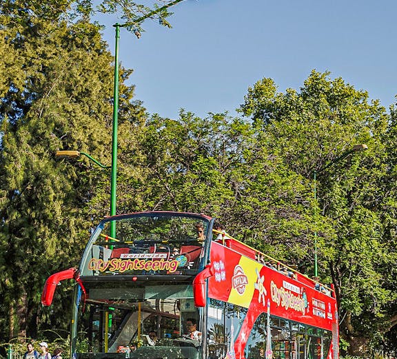 Red double-decker sightseeing bus in Budapest with tourists on board.