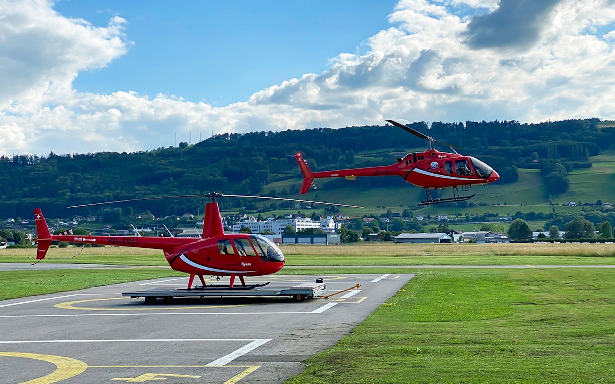 Helicopter taking off from Bern-Belp Airport with Stockhorn Mountain in the background.