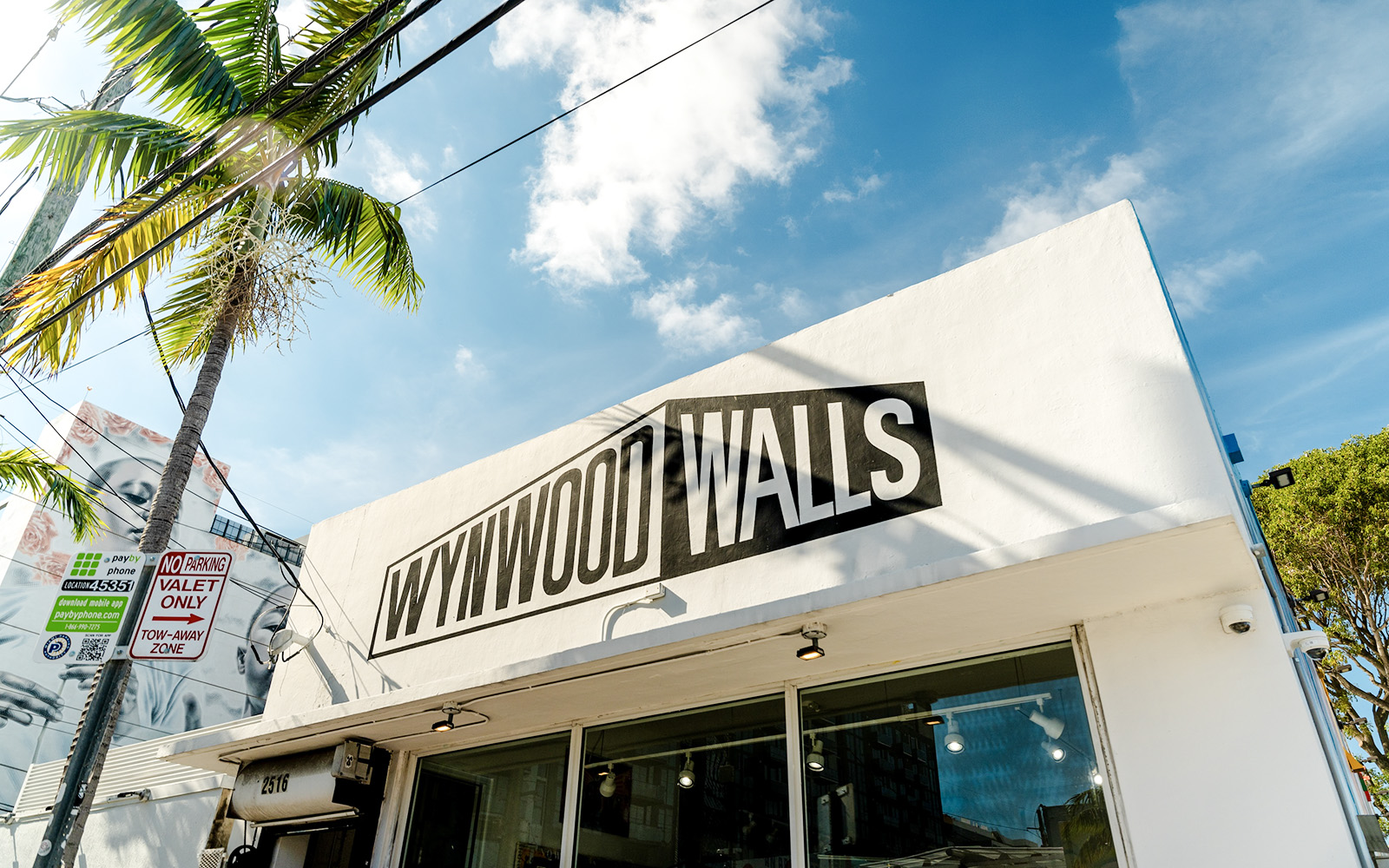 Wynwood Walls Museum entrance with palm tree and street signs in Miami.