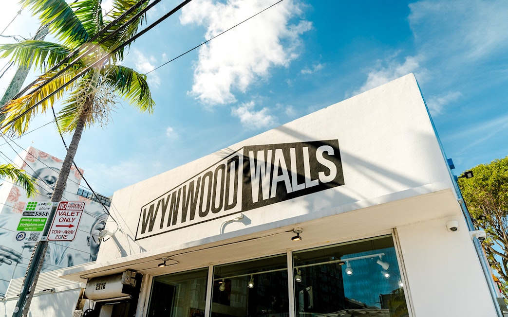 Wynwood Walls Museum entrance with palm tree and street signs in Miami.