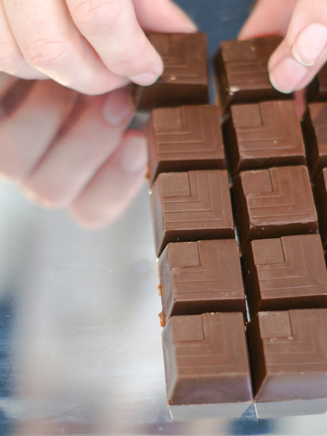 Hands arranging chocolate squares at Choco-Story Brussels Museum.