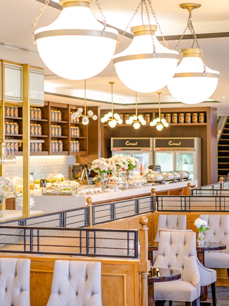 Dining area at The Coral Executive Lounge, Bangkok Airport, featuring elegant seating and buffet setup.