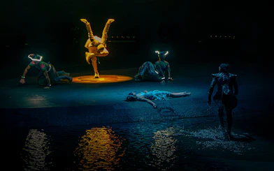 Acrobats performing at La Perle show in Dubai with water reflections.
