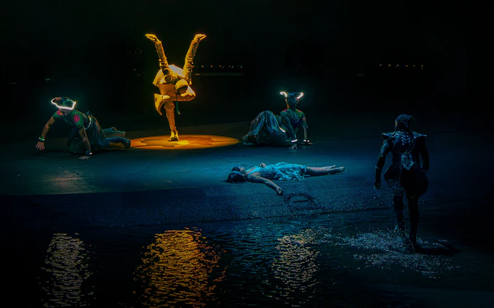 Acrobats performing at La Perle show in Dubai with water reflections.