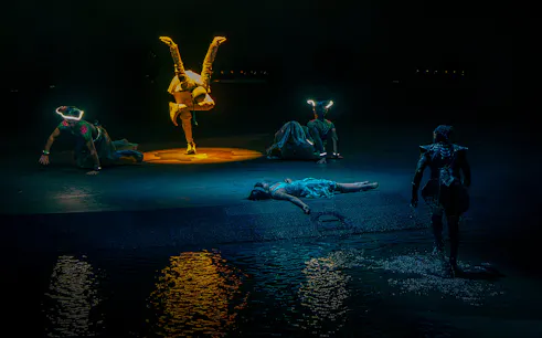 Acrobats performing at La Perle show in Dubai with water reflections.