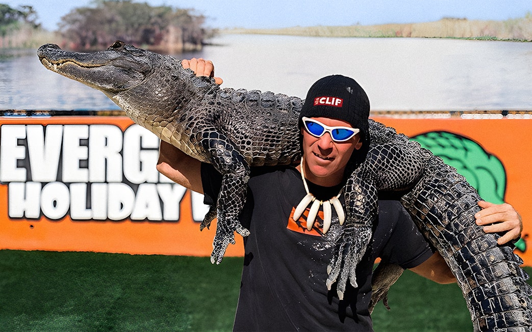 Man holding an alligator at Holiday Park during airboat tour and wildlife show.
