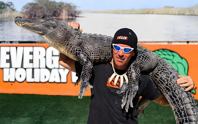 Man holding an alligator at Holiday Park during airboat tour and wildlife show.