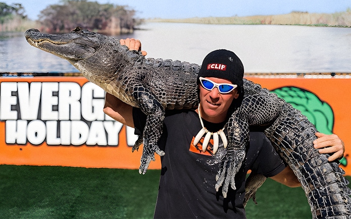 Man holding an alligator at Holiday Park during airboat tour and wildlife show.