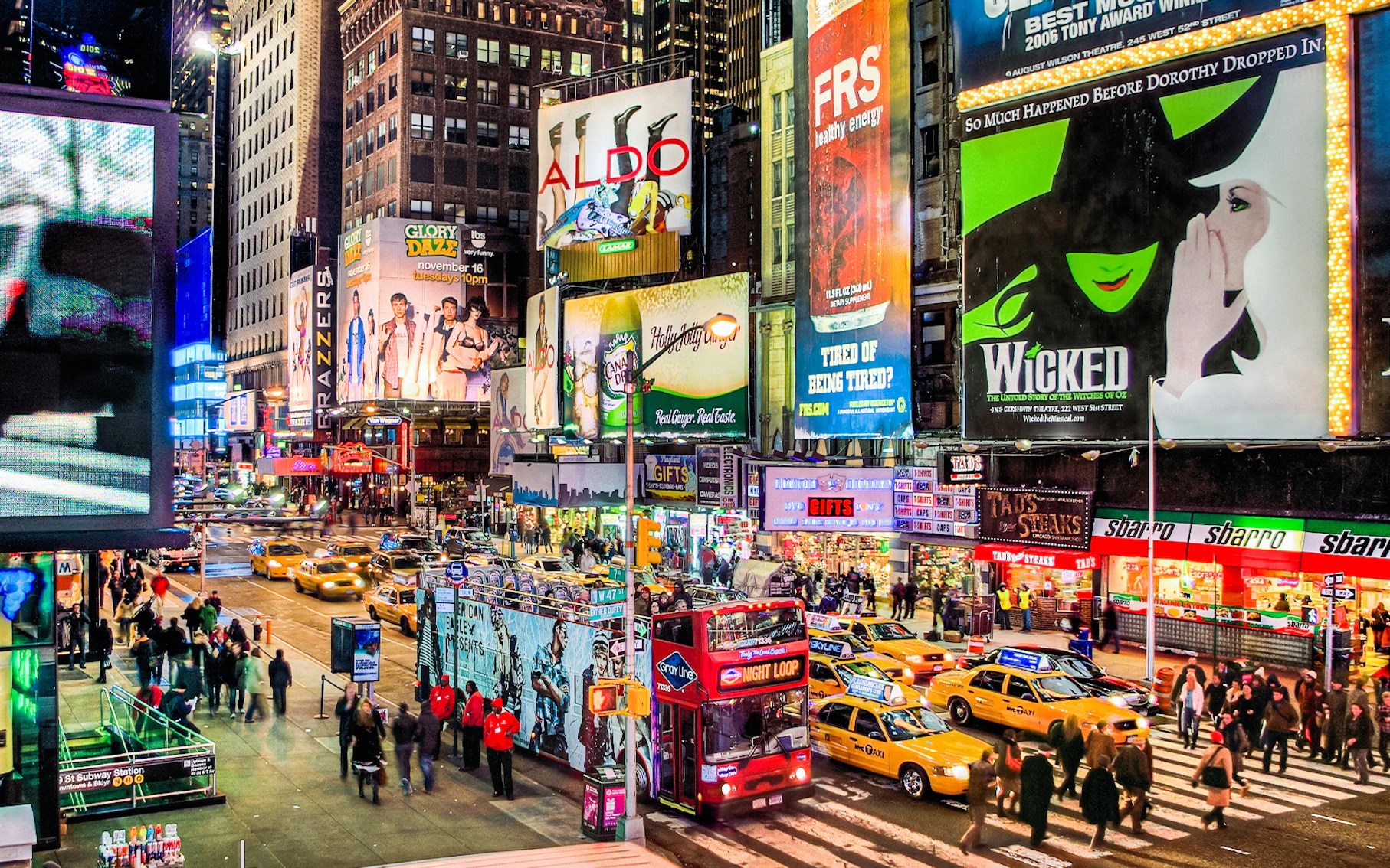 Times Square at night with Broadway show billboards and busy street scene.