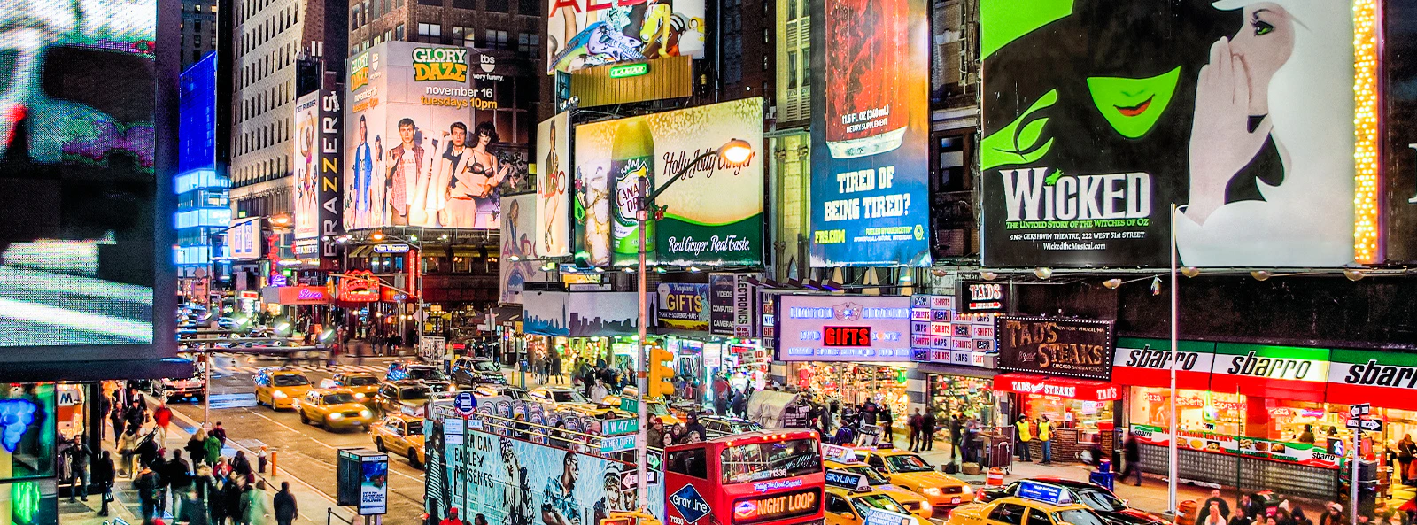 Times Square at night with Broadway show billboards and busy street scene.