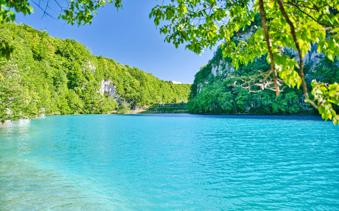Plitvice Lakes turquoise water surrounded by lush green forest.