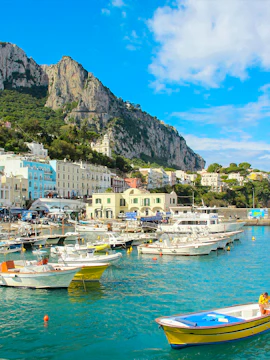 Boats docked at Marina Grande with cliffs in Capri, Italy, part of Rome to Capri tours.