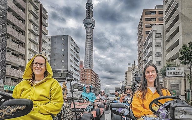 People in costumes driving go-karts near Tokyo Skytree.