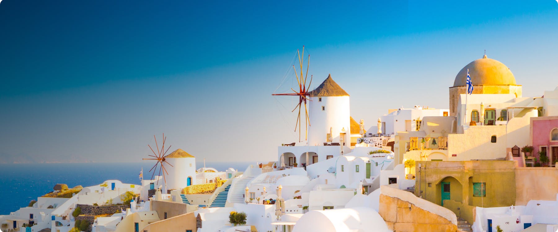 White buildings and windmills overlooking the sea in Mykonos, Greece.