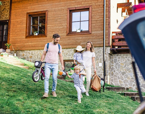 Family enjoying a day at Landsborough Holiday Park, carrying picnic and sports gear.