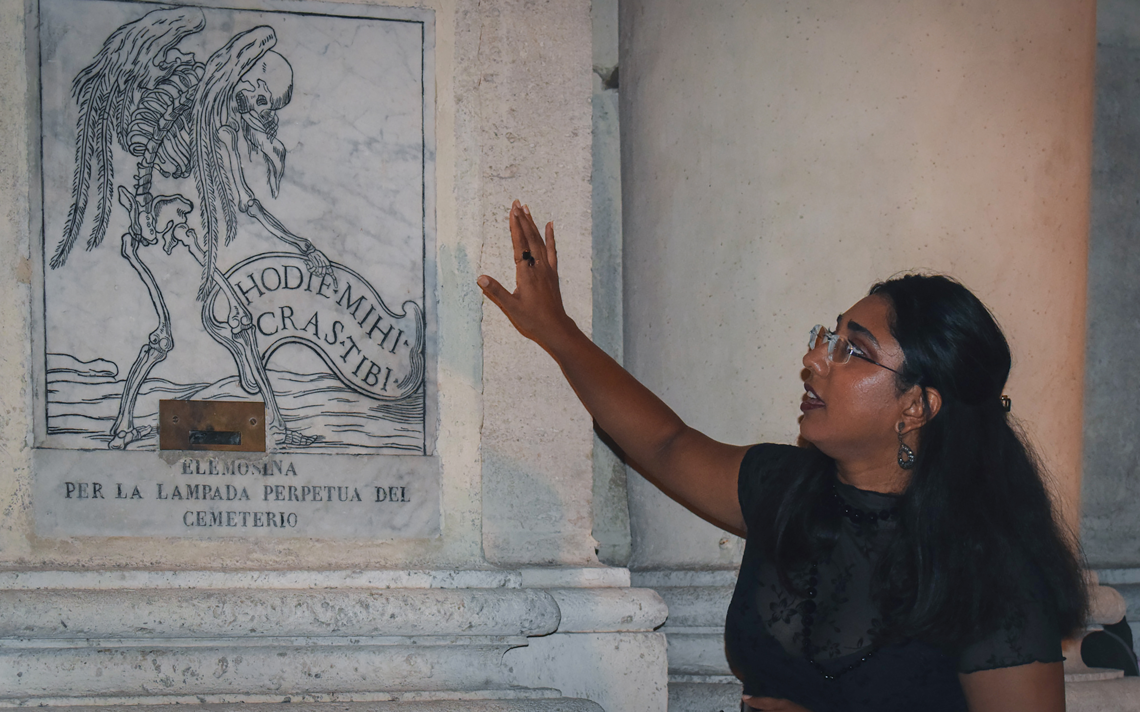 Person explaining a skeleton engraving on a wall during a ghost walking tour in Rome.
