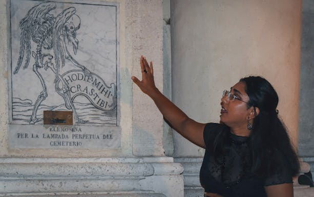 Person explaining a skeleton engraving on a wall during a ghost walking tour in Rome.