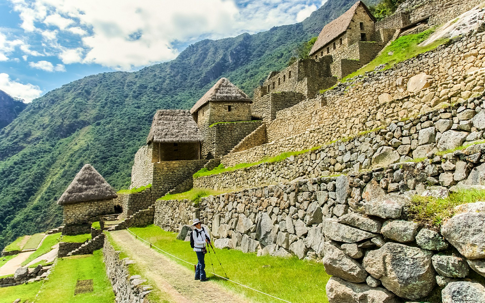 Hiker walking along stone terraces in the agricultural area of Machu Picchu, Peru.