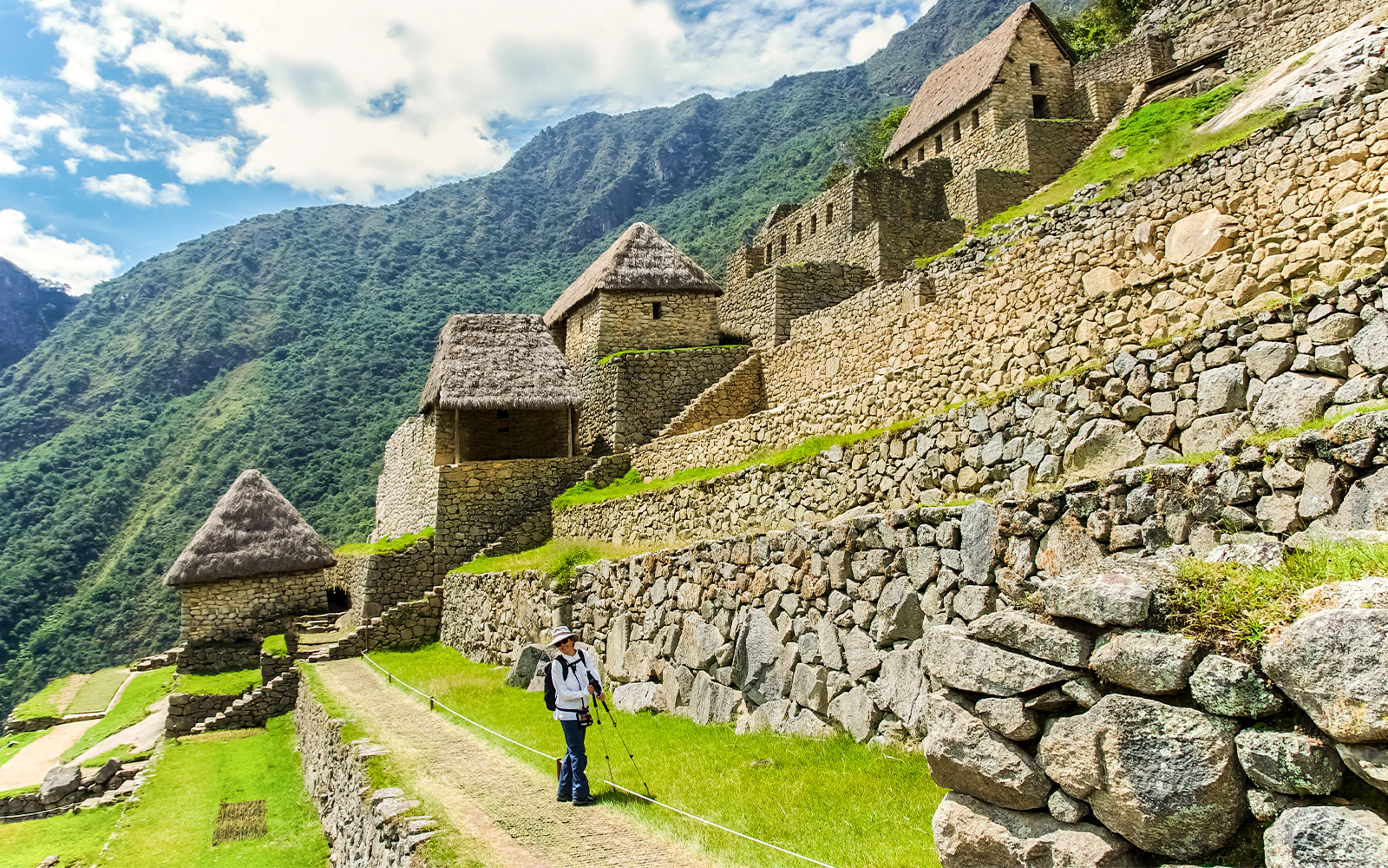 Hiker walking along stone terraces in the agricultural area of Machu Picchu, Peru.
