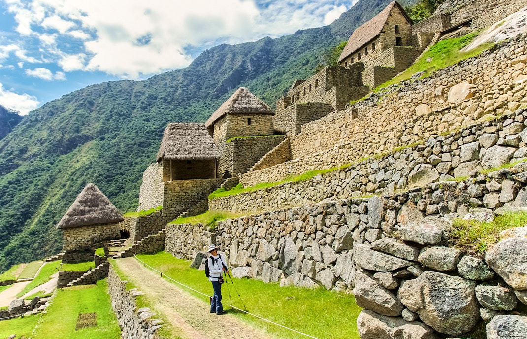 Hiker walking along stone terraces in the agricultural area of Machu Picchu, Peru.