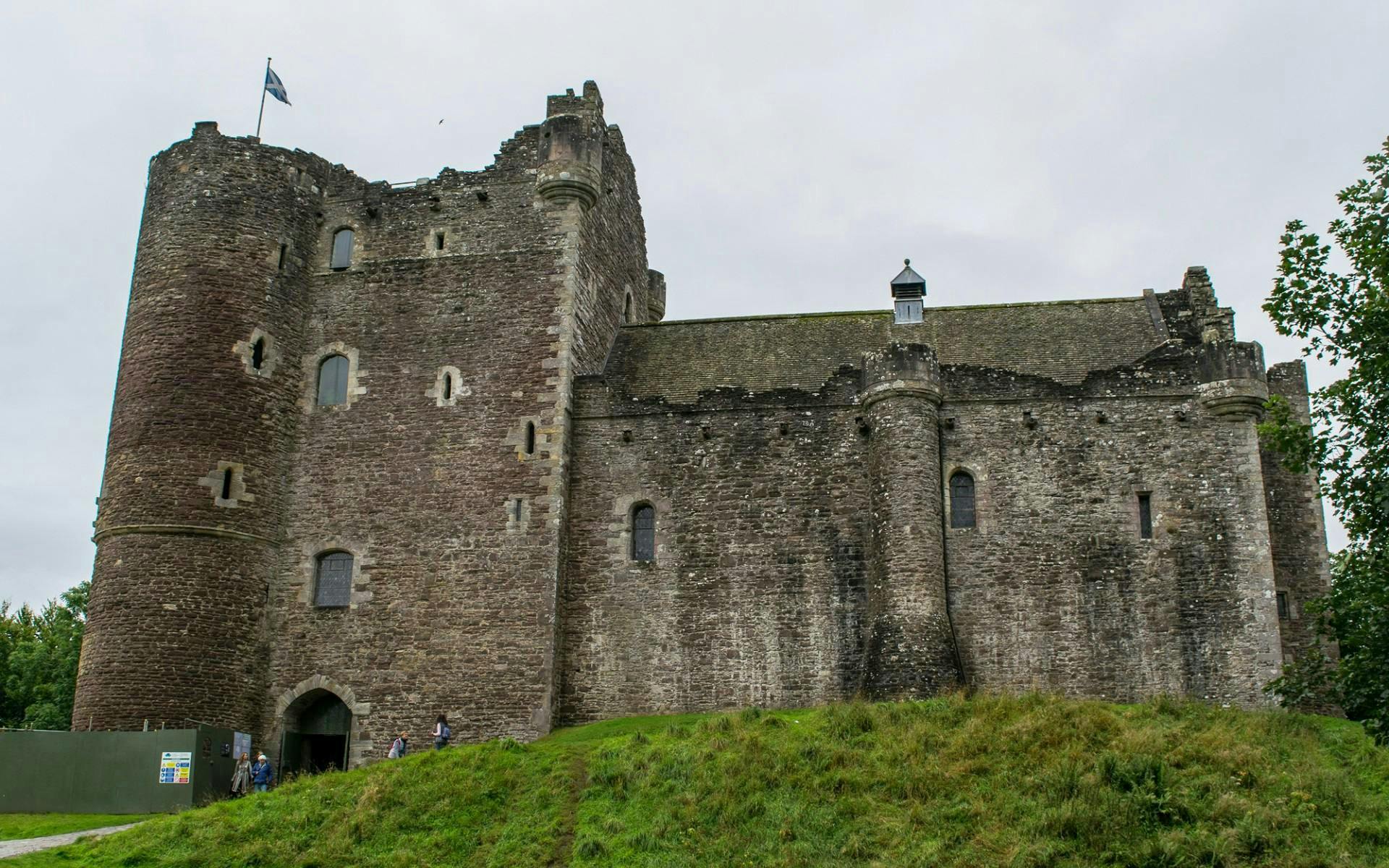 Doune Castle in Scotland with stone walls and a flag on the tower.