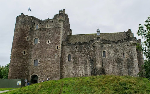 Doune Castle in Scotland with stone walls and a flag on the tower.