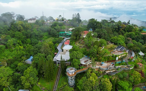 Aerial view of lush greenery and buildings on Penang Hill, Malaysia, near the funicular train route.