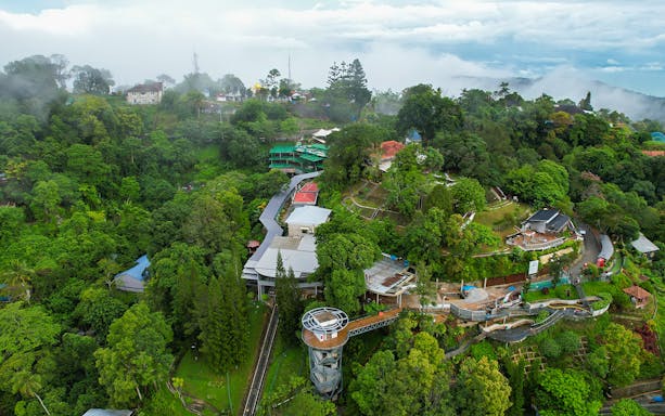 Aerial view of lush greenery and buildings on Penang Hill, Malaysia, near the funicular train route.