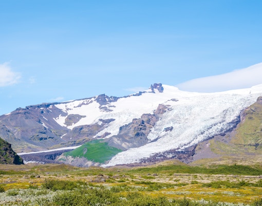 Falljokull glacier in Iceland with rugged mountains and green landscape.