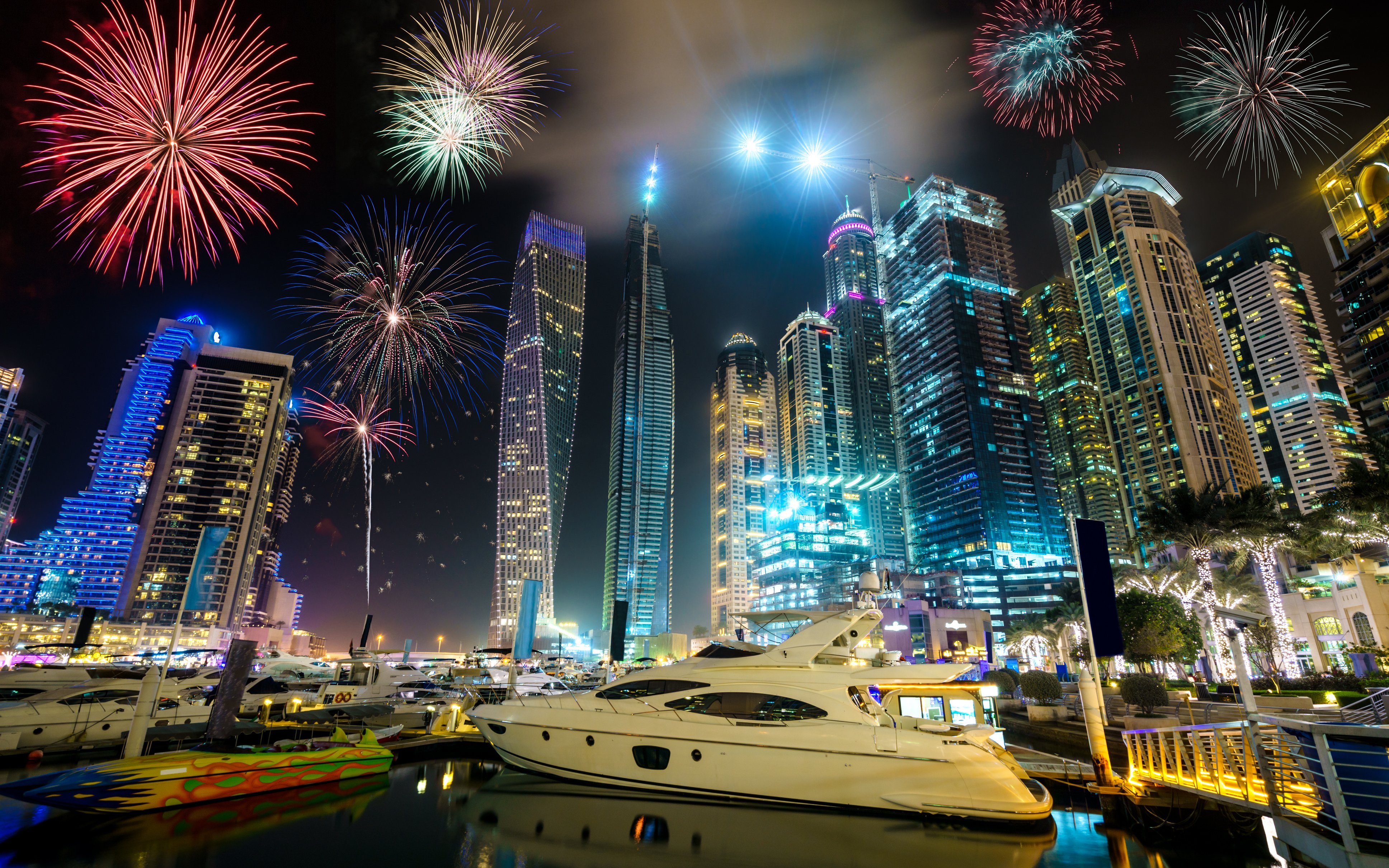 Fireworks over Dubai Marina with yachts and skyscrapers illuminated at night, UAE.