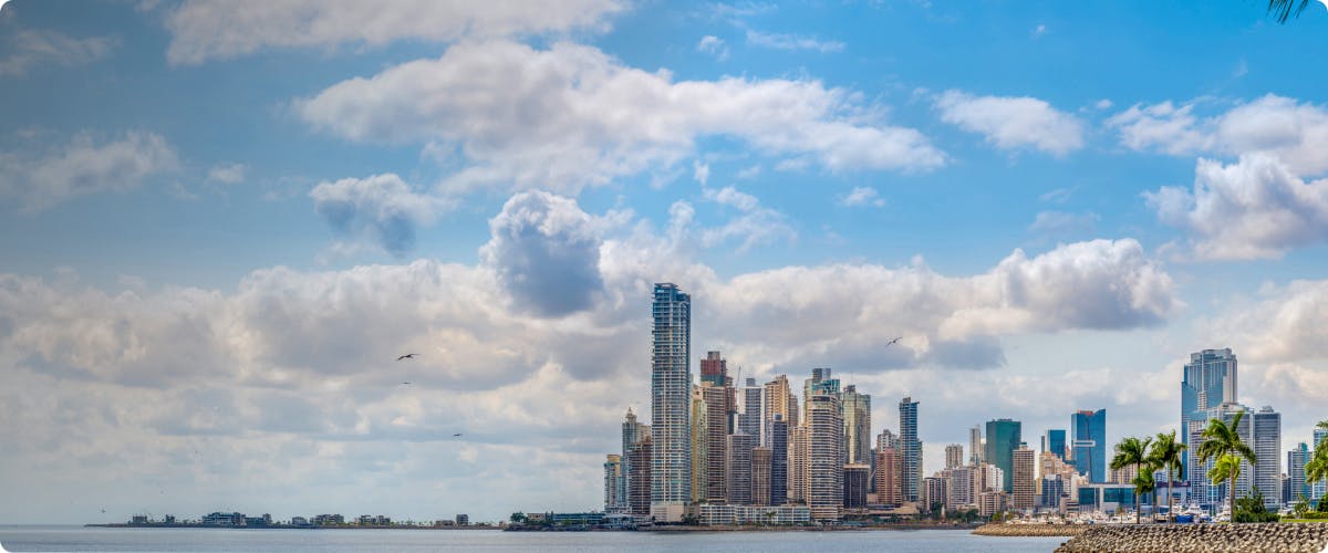 Panama City skyline with high-rise buildings along the waterfront under a cloudy sky.