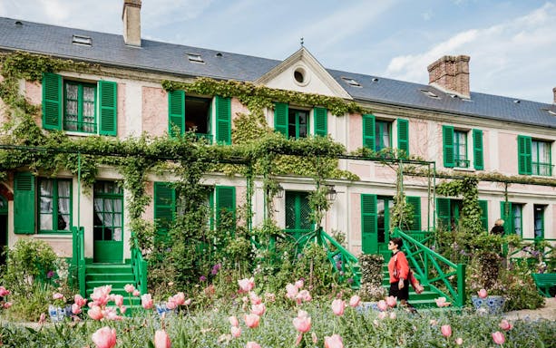 Giverny house with green shutters and blooming garden, part of Musée d'Orsay and Giverny tour.