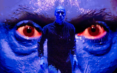 Blue Man Group performer on stage with large blue face backdrop, Orlando.
