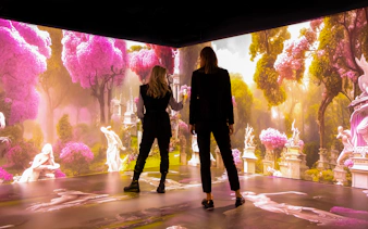 Visitors exploring immersive Mythos Mozart exhibit with vibrant pink trees and classical statues.