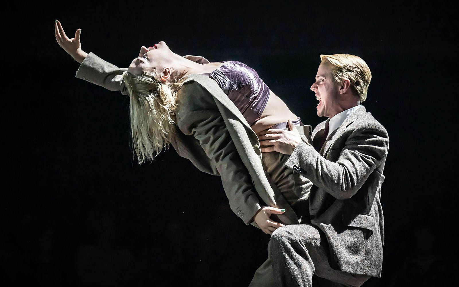 Performers in a dramatic cabaret scene on stage.