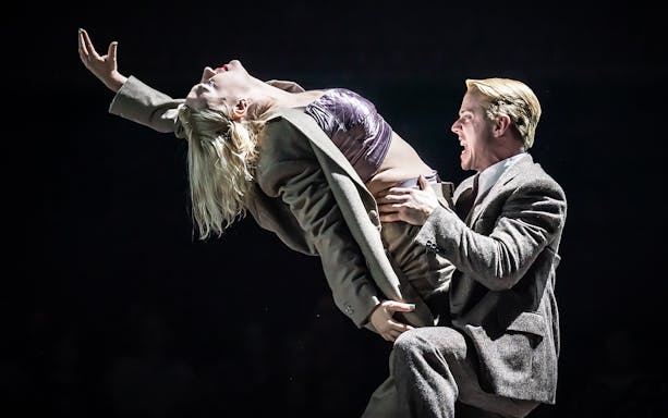 Performers in a dramatic cabaret scene on stage.