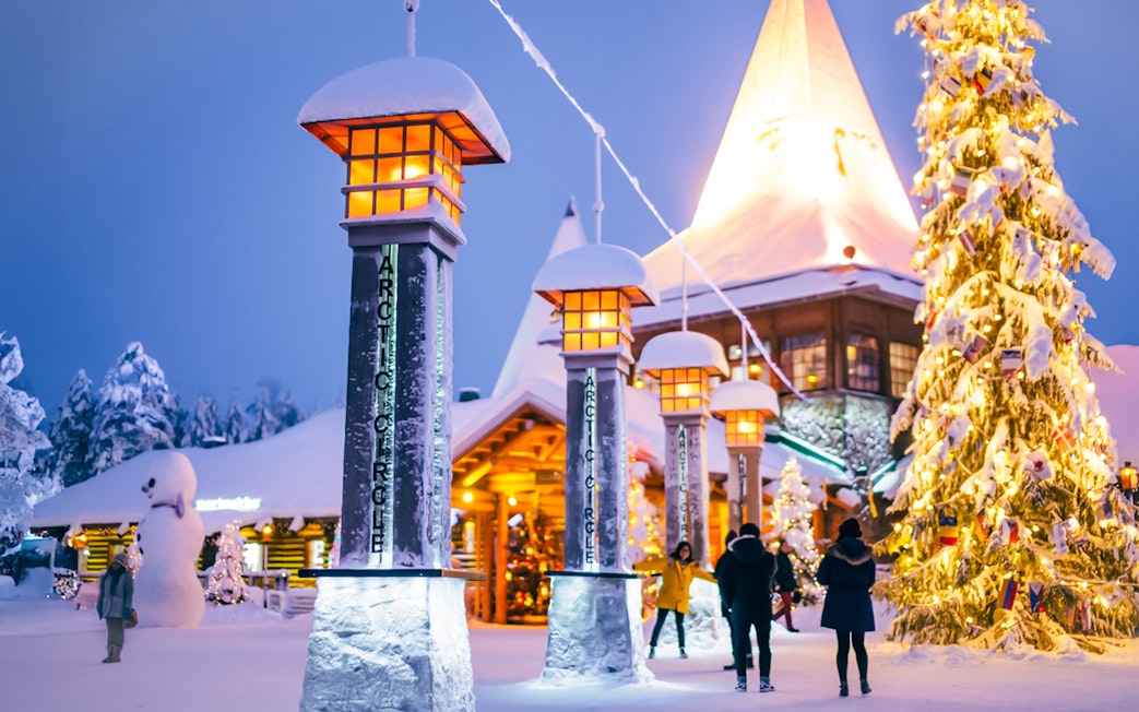 Central plaza of Santa’s Village with illuminated Arctic Circle markers and festive decorations.