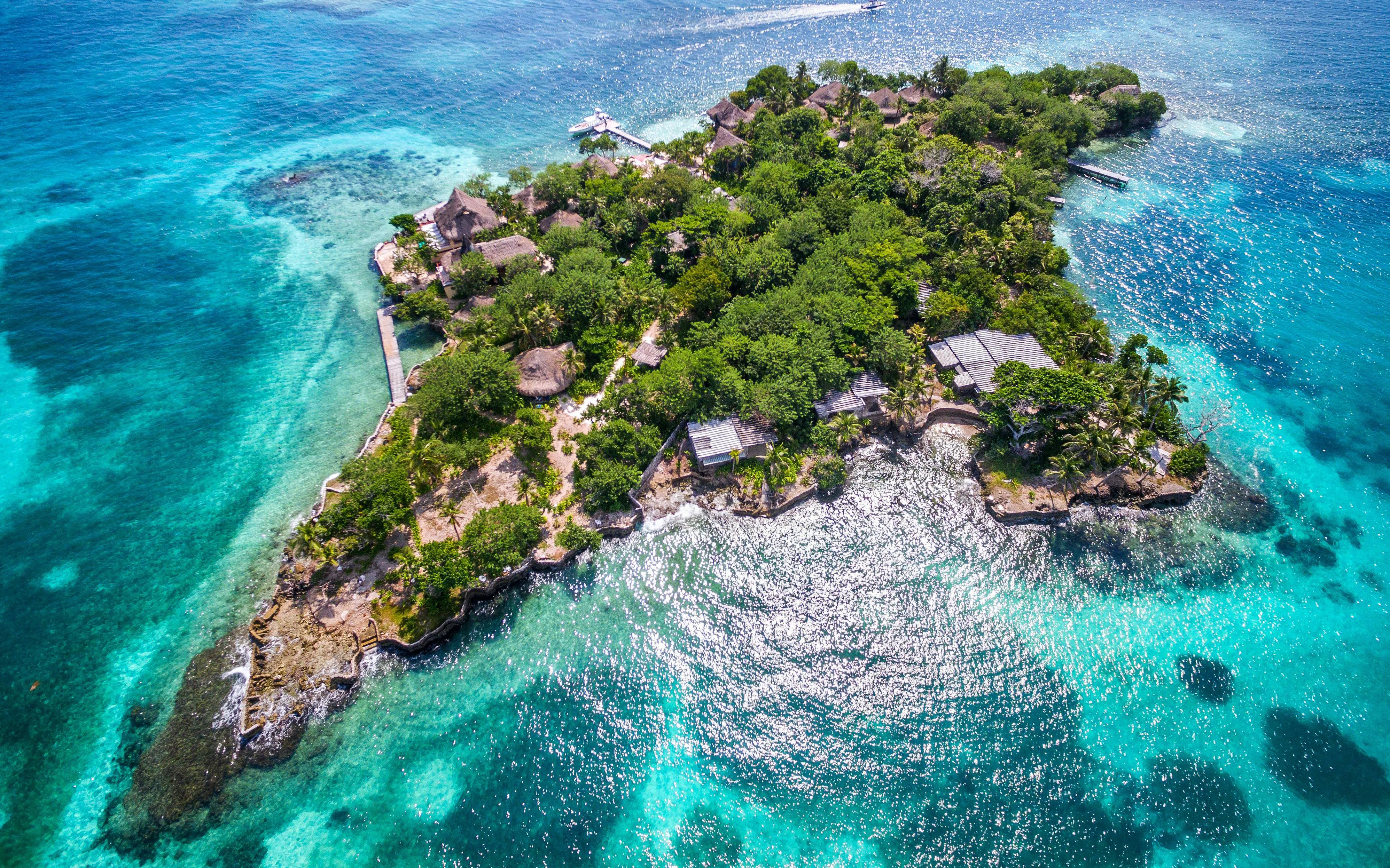 Aerial view of Isla del Pirata, lush greenery surrounded by turquoise waters, Rosario Islands, Colombia.